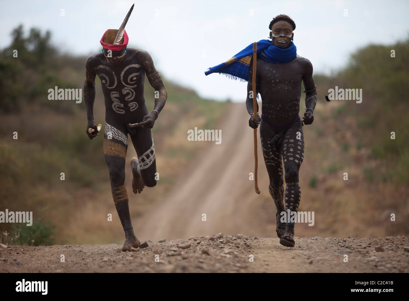 Due guerrieri che corrono dei Mursi Village, Valle dell'Omo, Etiopia Foto Stock