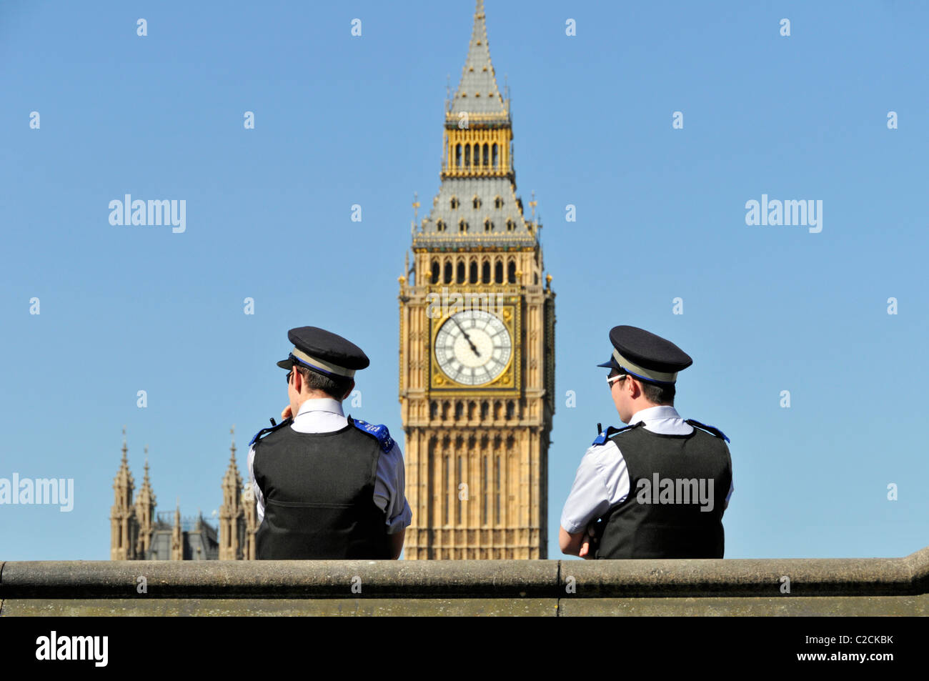 Due di un genere di funzionari di sostegno della comunità della polizia metropolitana con Big ben Beyond in una giornata di primavera nel cielo blu a Westminster Londra Inghilterra Regno Unito Foto Stock