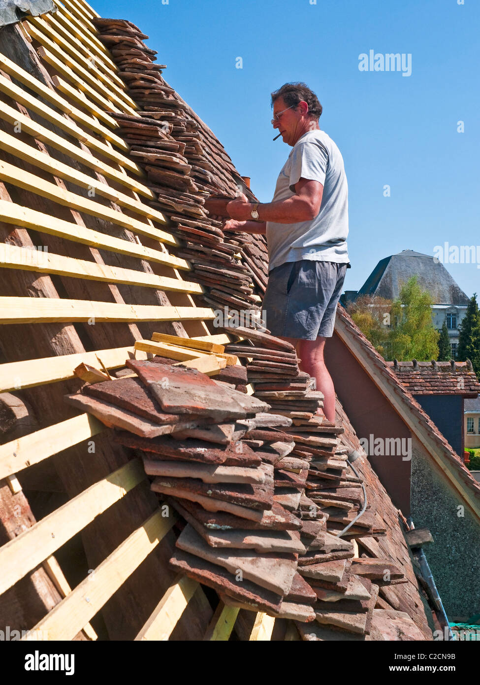 Workman sostituisce le vecchie tegole su listelli di nuovo - Francia. Foto Stock