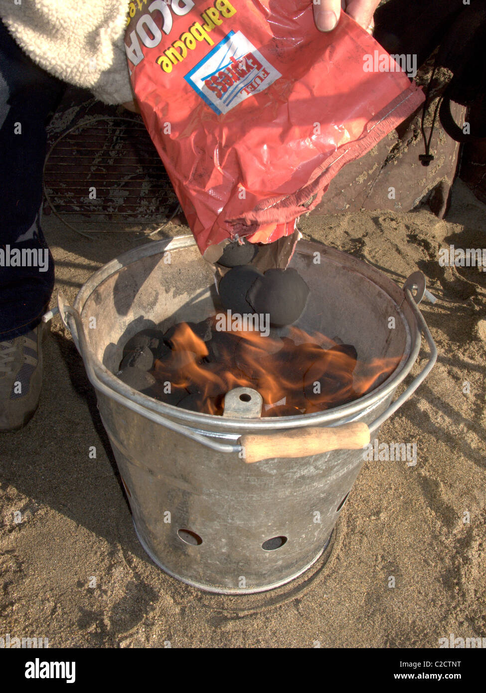 Alimentazione di carbone in una accesa barbecue sulla spiaggia Foto Stock