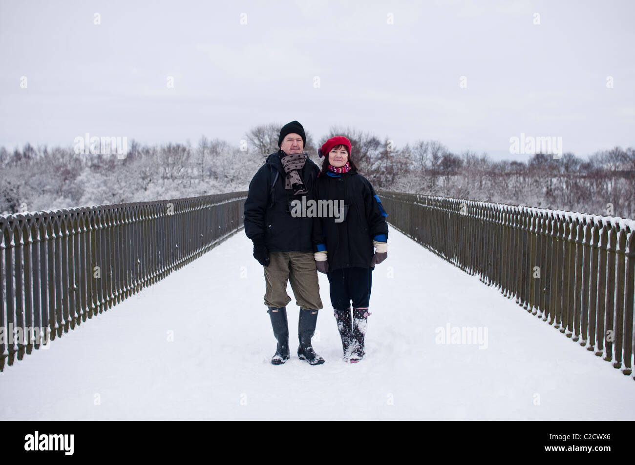 Un ritratto di una coppia di mezza età su un inverno nevoso a piedi attraverso il viadotto Hownsgill nella Contea di Durham, Inghilterra, Regno Unito. Foto Stock