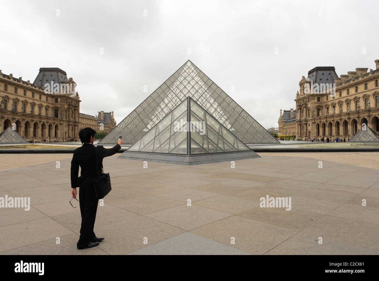 Uomo di scattare una foto con la fotocamera di un cellulare in del Louvre Napoleone cortile con I.M. Pei la piramide in vetro. Foto Stock