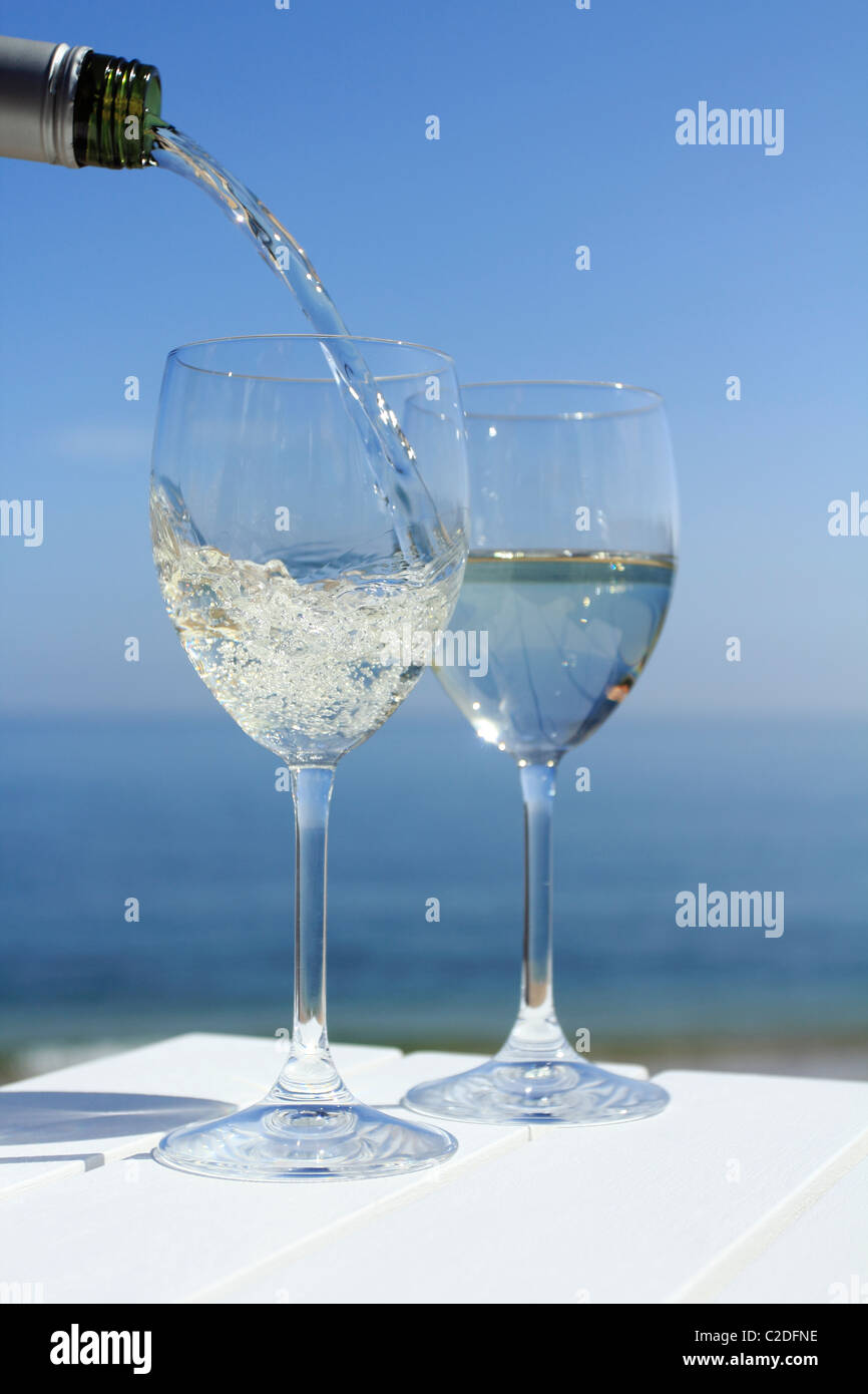 Versando il vino in riva al mare Foto Stock