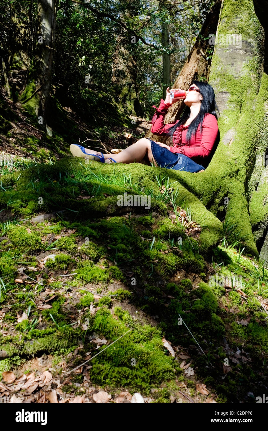 Giovane donna relax su un muschio coperto banca in un luminoso bosco Foto Stock