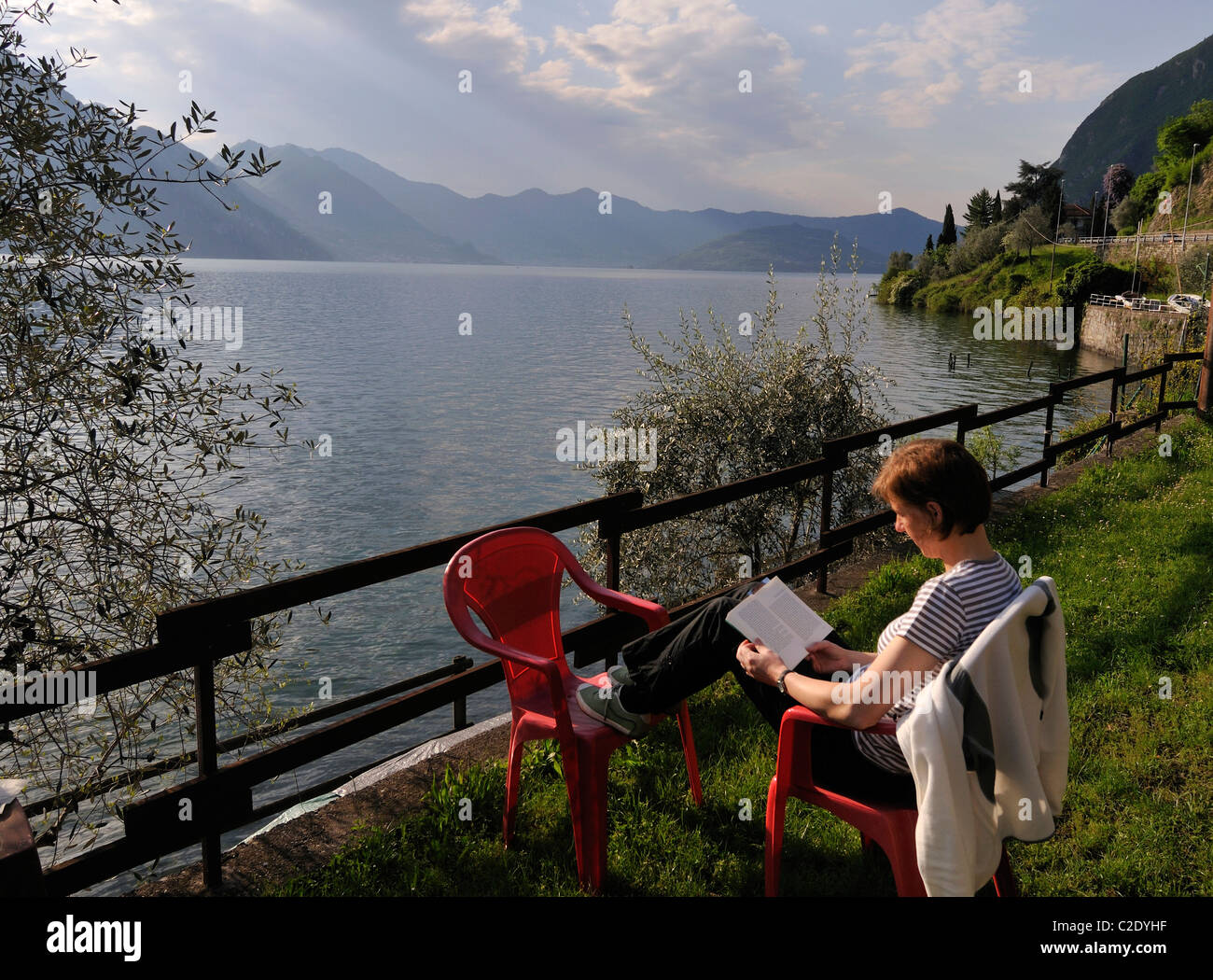 Donna seduta e la lettura al Lago d Iseo a Riva di Solto, Bergamo, Italia Foto Stock