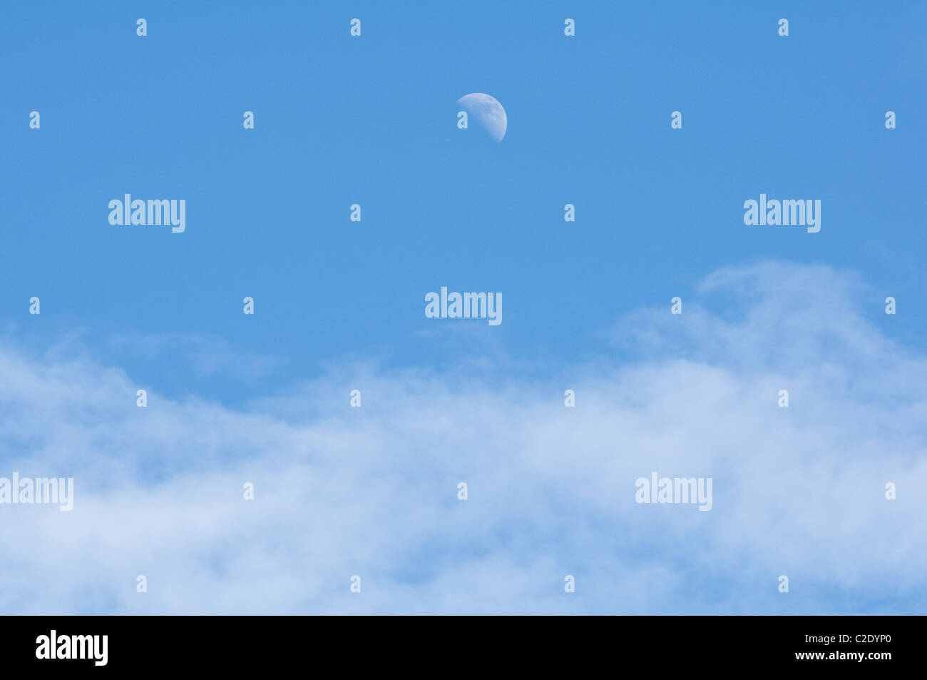 Half Moon visto durante le ore diurne, con la metà di cielo blu e wispy nuvole bianche in primo piano. Foto Stock