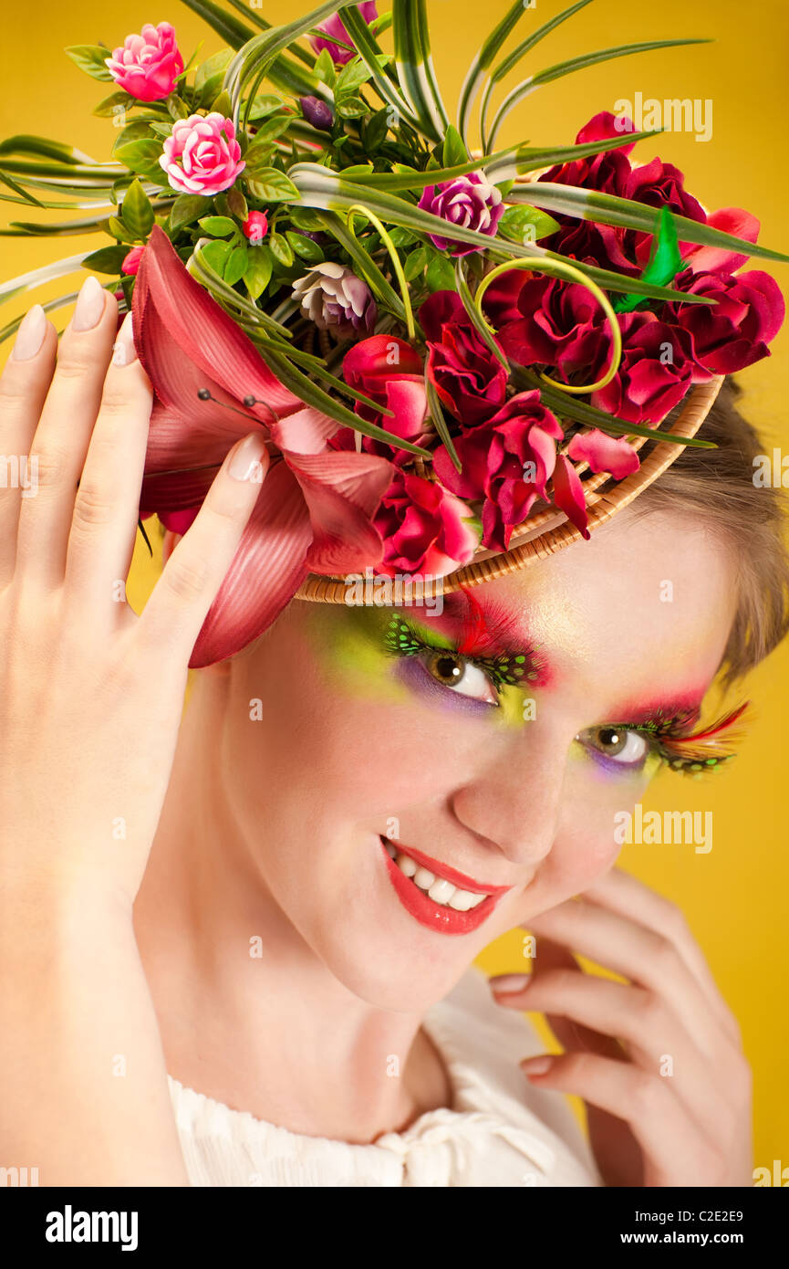 Bella giovane donna con fiore creative cap. Trucco Artistico con una lunga piuma ciglia artificiali Foto Stock