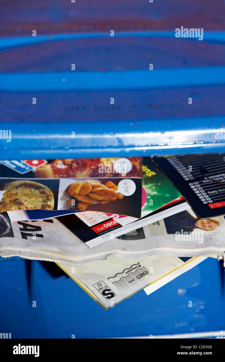 Carta blu il contenitore di riciclaggio con la posta indesiderata e i quotidiani locali fuori di esso e il coperchio non chiuso nel Regno Unito Foto Stock