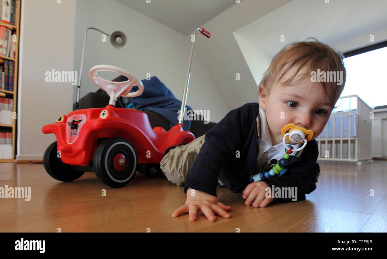 Little Boy, baby, 10 mesi, giocando con un Bobby auto a casa. Foto Stock