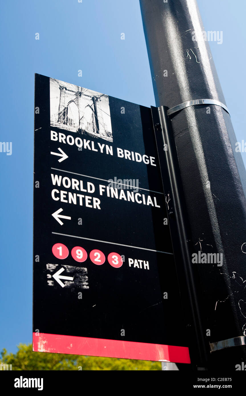 Informazioni turistiche firmare con il ponte di Brooklyn e il World Financial Center di Manhattan, New York City, Stati Uniti d'America Foto Stock