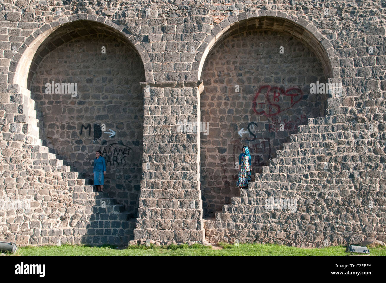 Due donne si trovano in una nicchia a forma di cuore nelle vecchie mura della fortezza di basalto della città curda di Diyarbakir, nella regione orientale dell'Anatolia della Turchia. Foto Stock