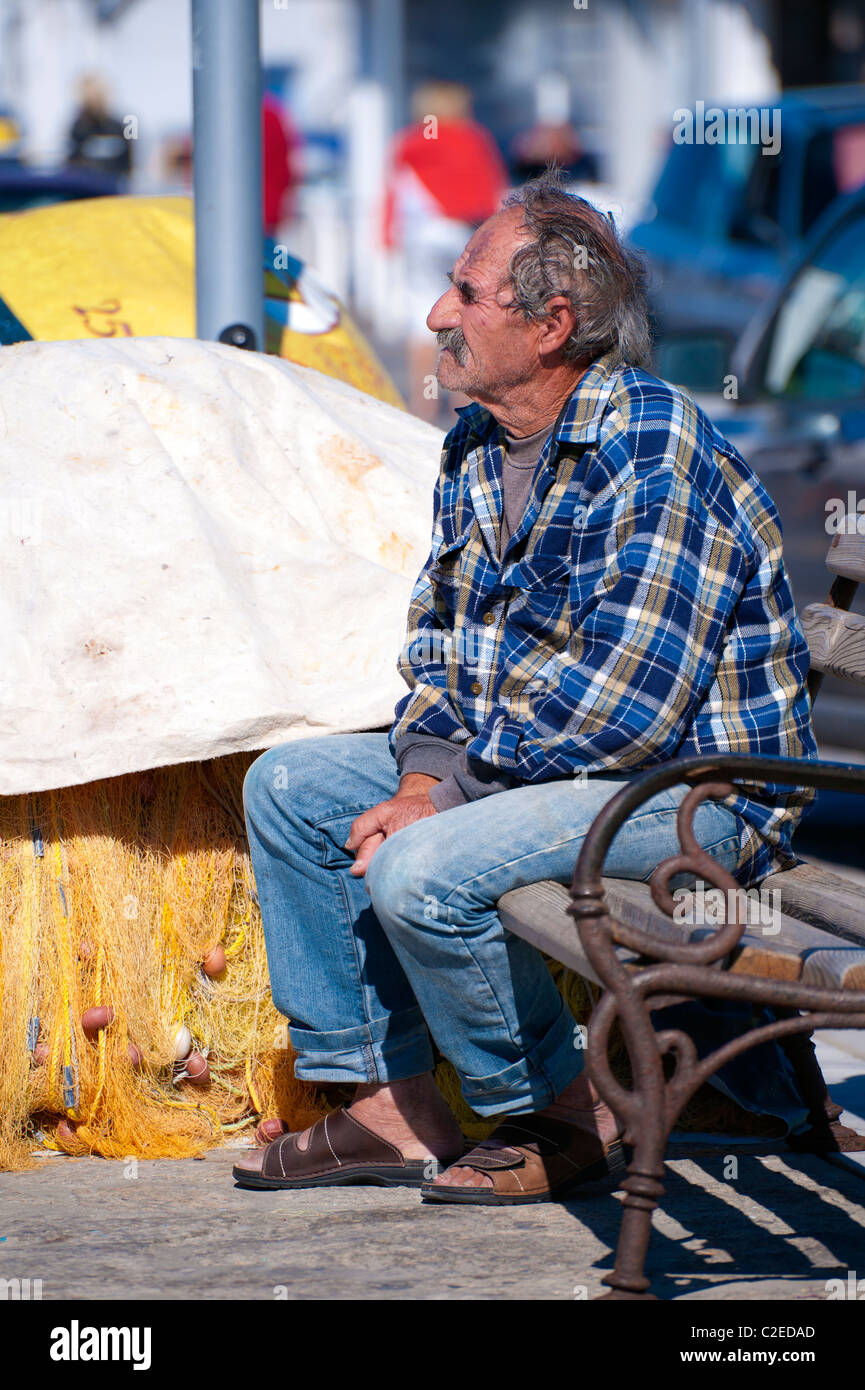 Pescatore greco seduta su una panchina nel porto di Naoussa, sul Greco Cyclade isola di Paros. Foto Stock