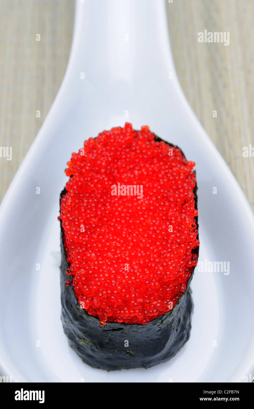 Vivacemente colorate di rosso Tobiko Flying Fish Roe (uova) su un rotolo di sushi Foto Stock