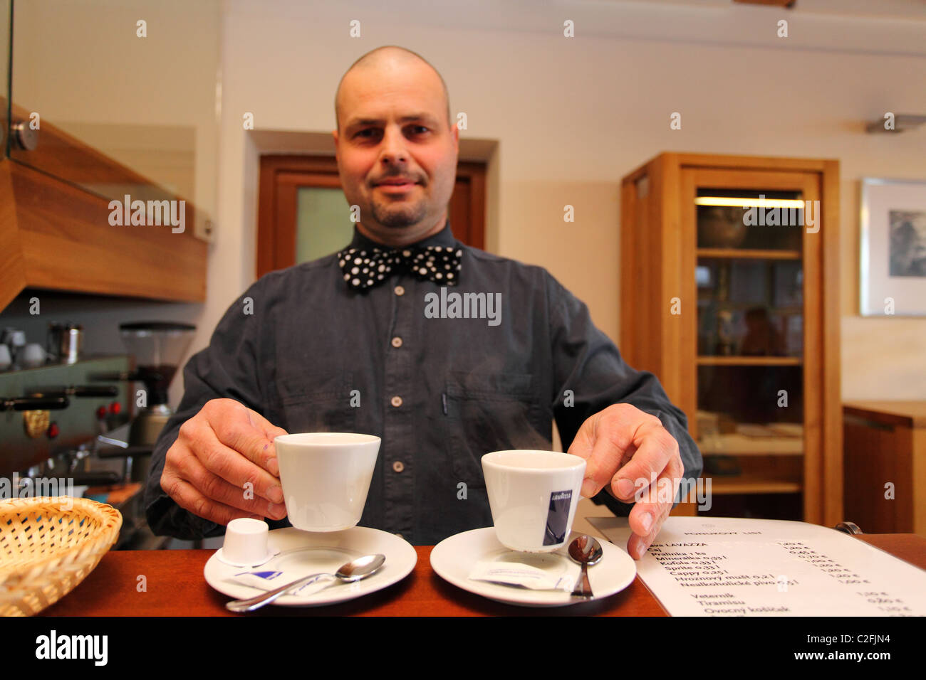 Barista che serve due tazze di caffè espresso. Foto Stock