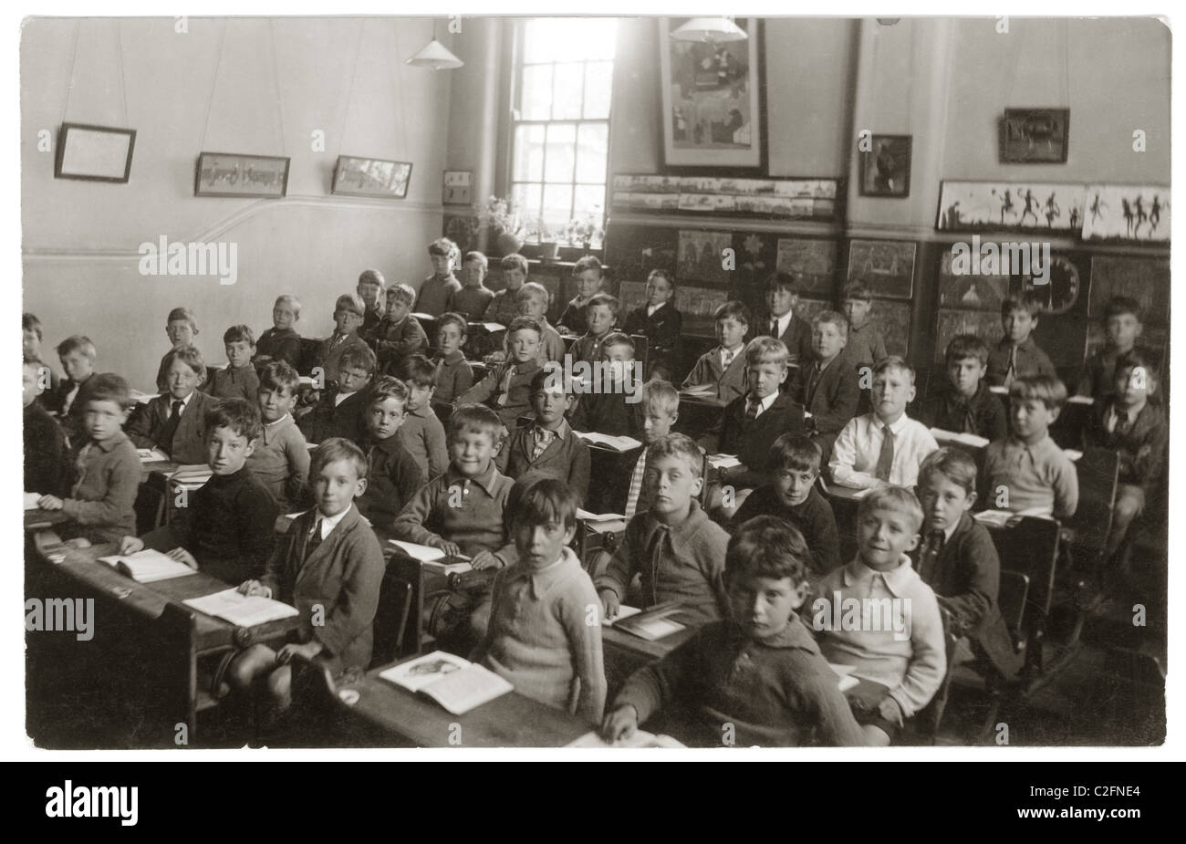 I neonati o junior ragazzi seduti alla scrivania con libri aperti in aula presso la scuola primaria - 1930 Foto Stock