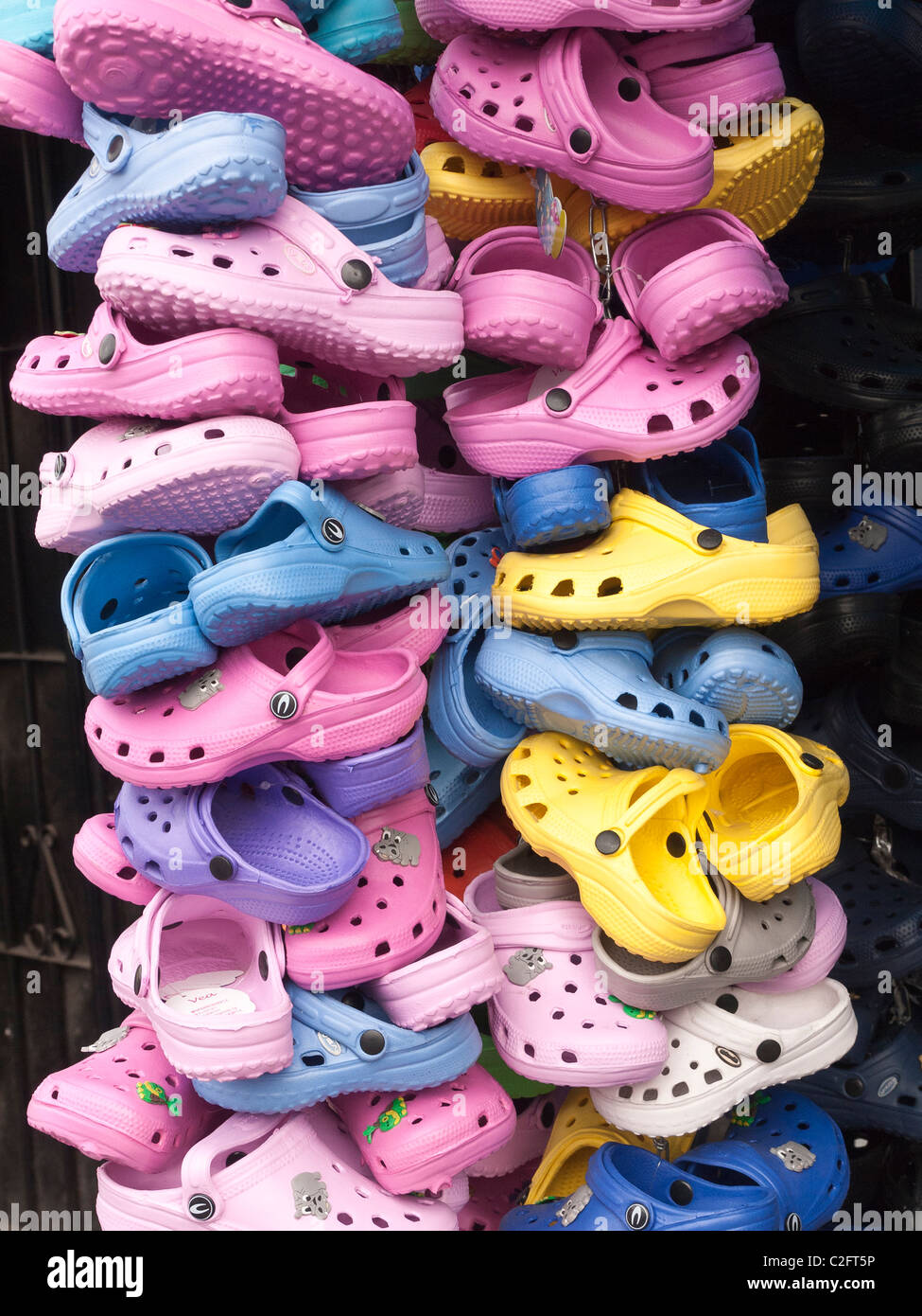 Una grande pila verticale di molti colori luminosi dei bambini del 'Croc'  scarpe, sandali di plastica tipo scarpe, sul visualizzatore in  corrispondenza di un fornitore sta Foto stock - Alamy