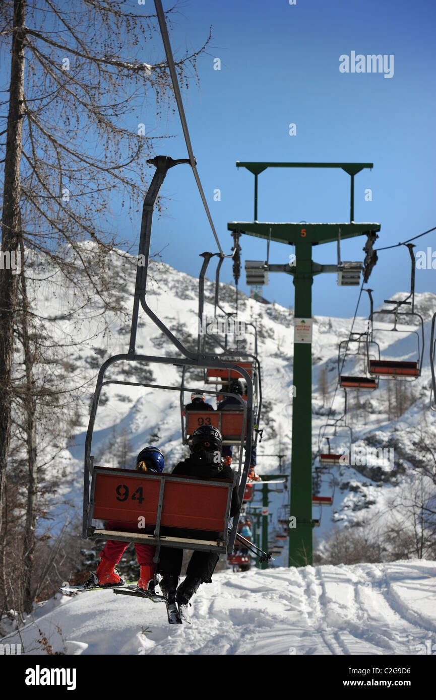 Gli sciatori in seggiovia al Vogel Ski Center dalla base del Sija - Zadnji Vogel piste del Parco Nazionale del Triglav di Slo Foto Stock