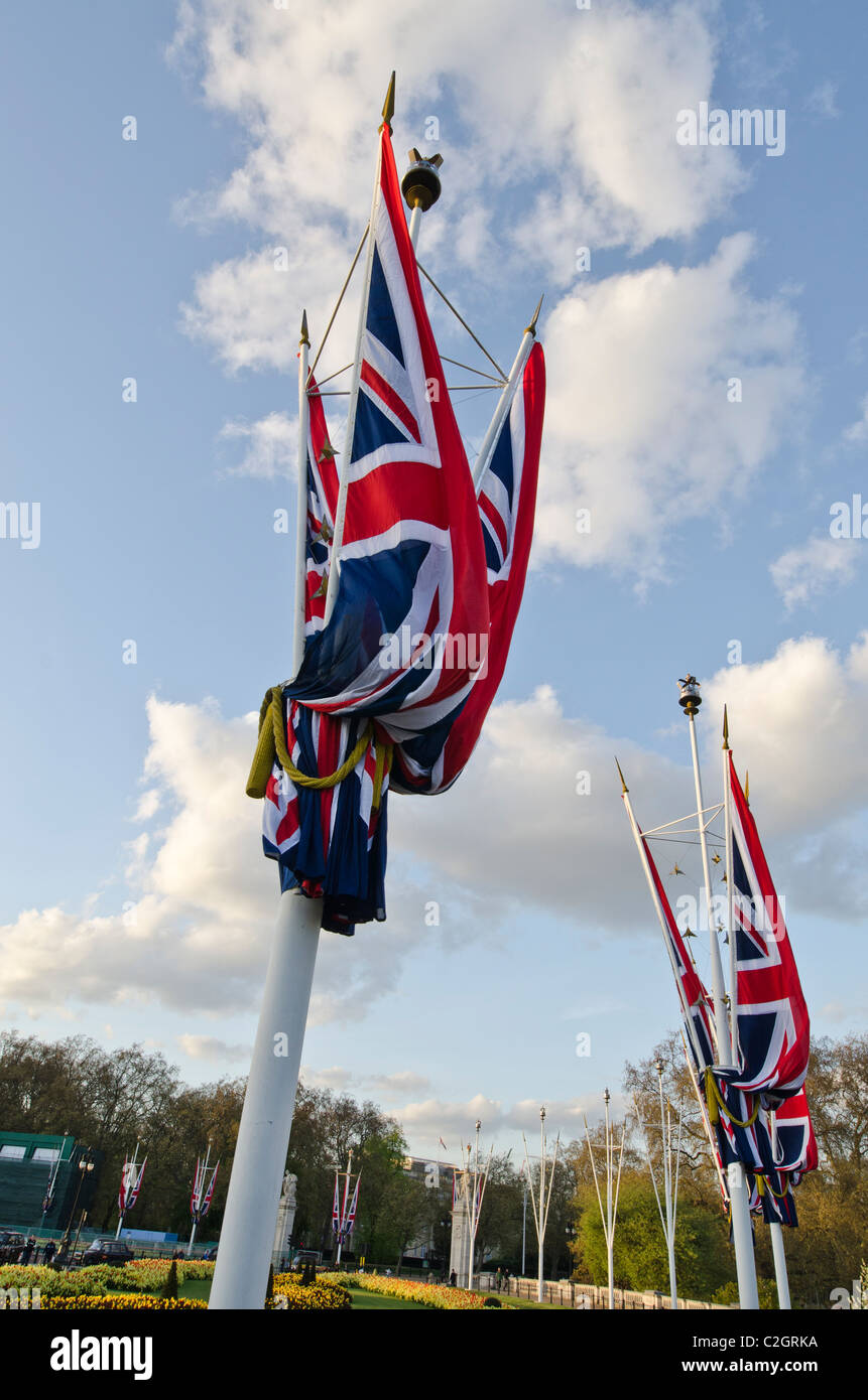 Union Jack flag su pali molla formale di biancheria da letto di fiori le piante al di sotto. Al di fuori del Palazzo di Buckingham Foto Stock
