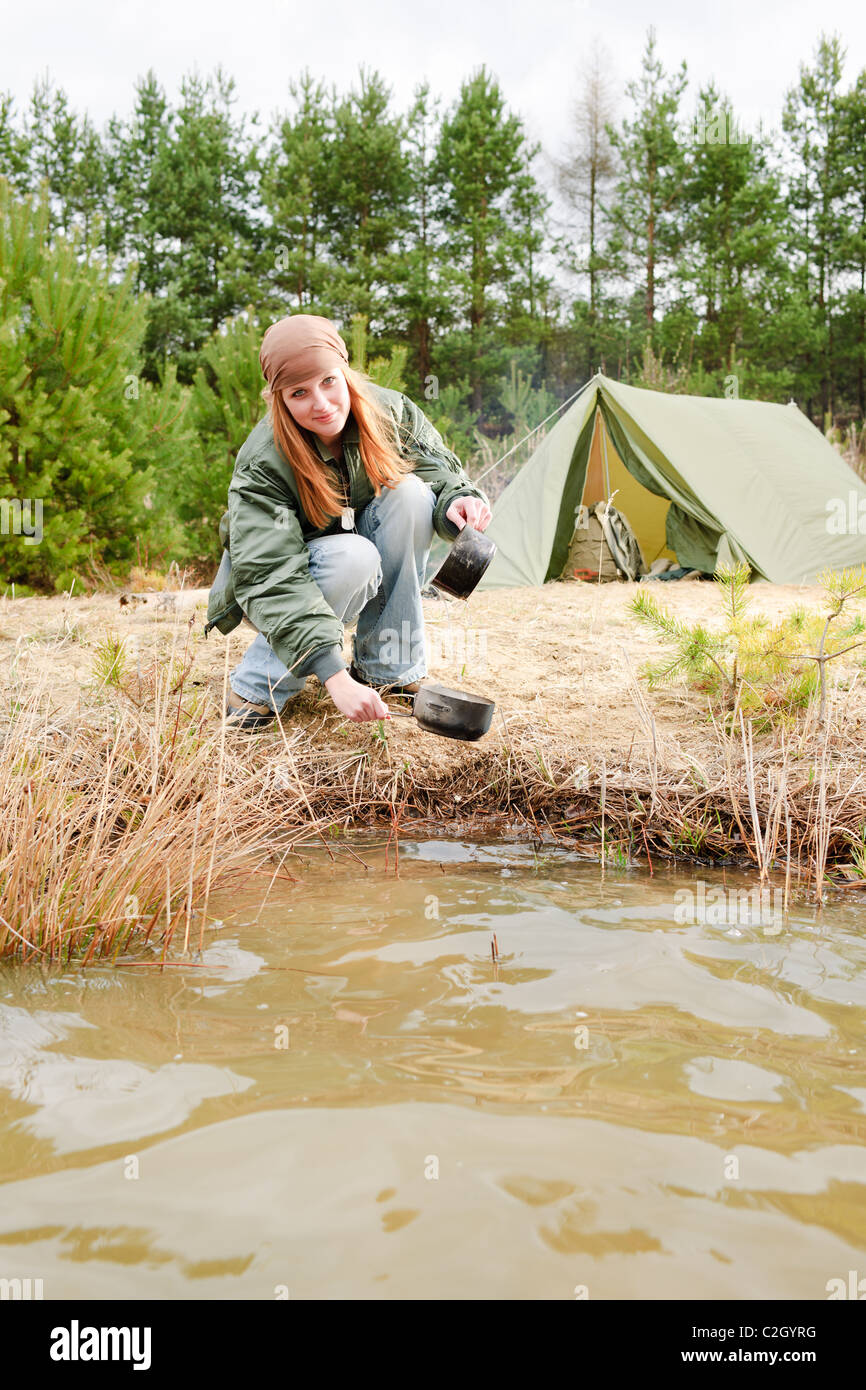 Tenda da campeggio donna felice lavaggio piatti nel flusso di acqua Foto Stock