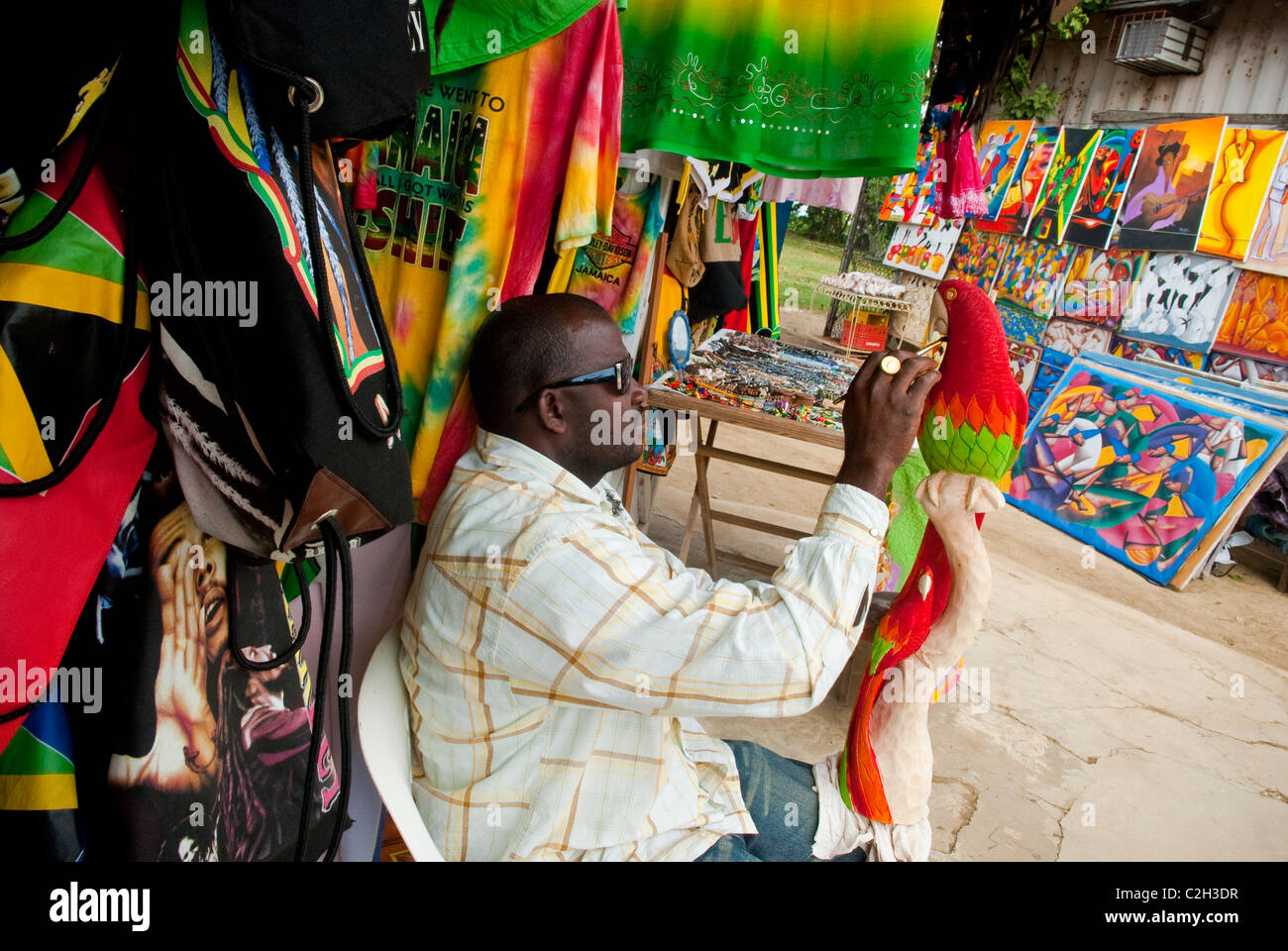 Artista " Glen' pittura una intagliata in legno bird a Negril Mercato di artigianato, vicino a Negril Town Center, Negril, Westmoreland, Giamaica Foto Stock