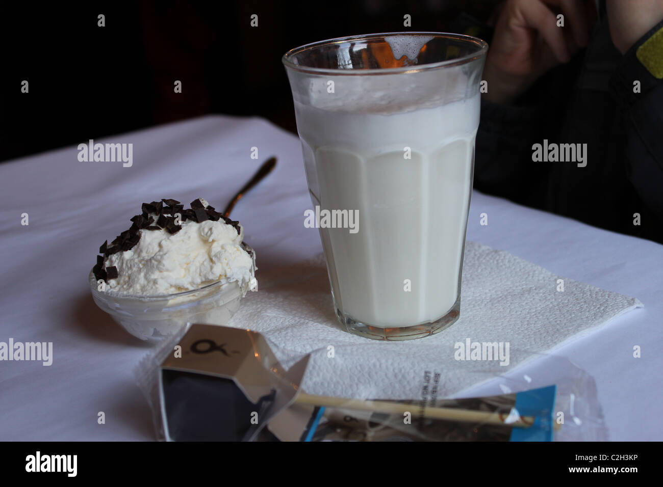 Un bicchiere di latte caldo con lecca-lecca al cioccolato per sciogliersi sul tavolo del caffè, Copenhagen Foto Stock