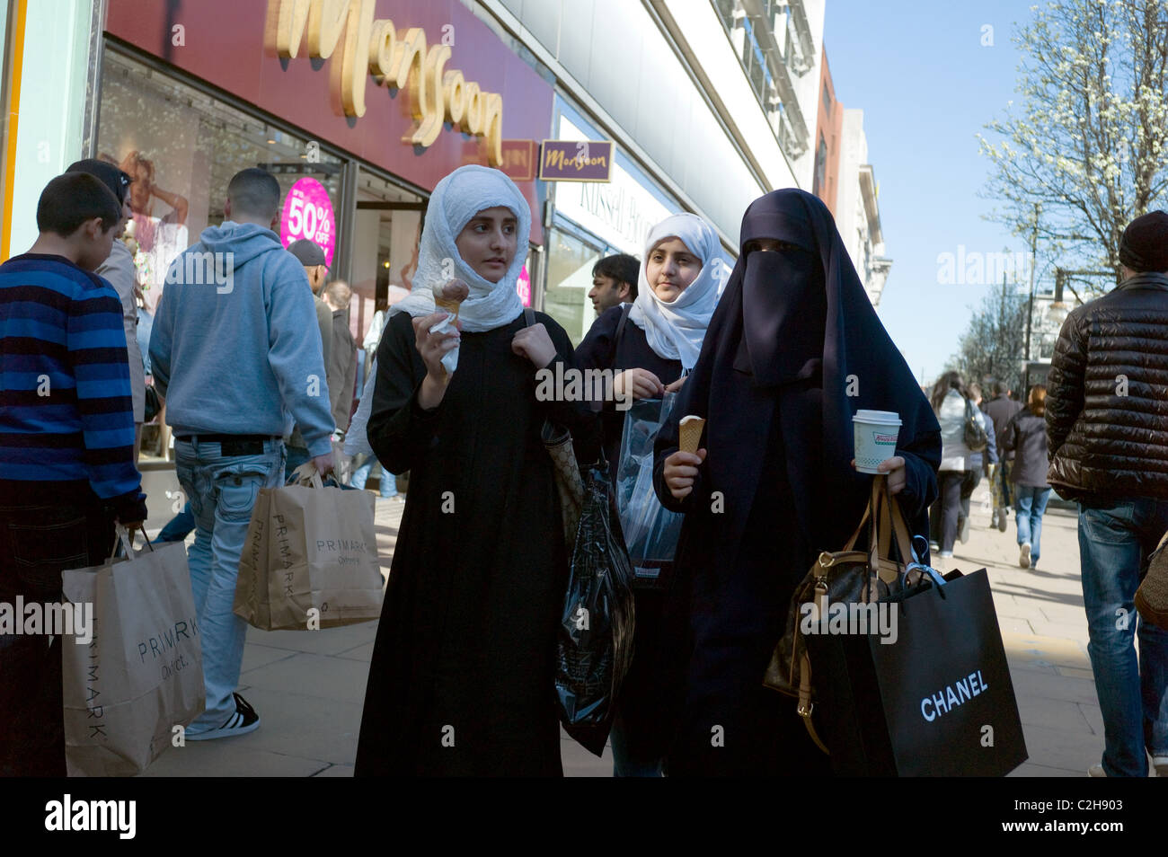 Un gruppo di giovani musulmani che gli acquirenti a mangiare il gelato su Oxford Street London REGNO UNITO Foto Stock