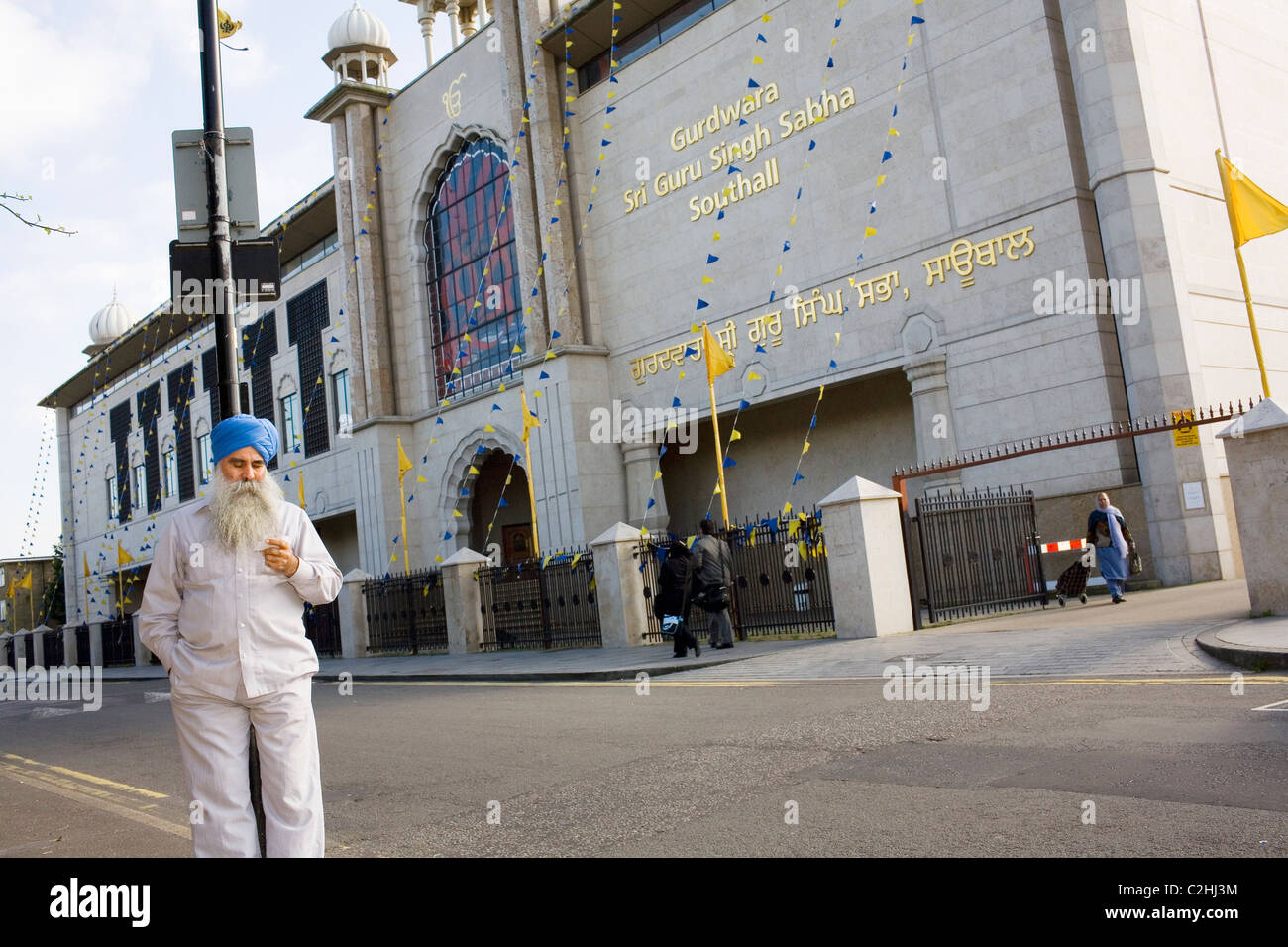 Un uomo Sikh si appoggia su una lampada posta al di fuori di un tempio di Southall, un occidente sobborgo londinese. Foto Stock
