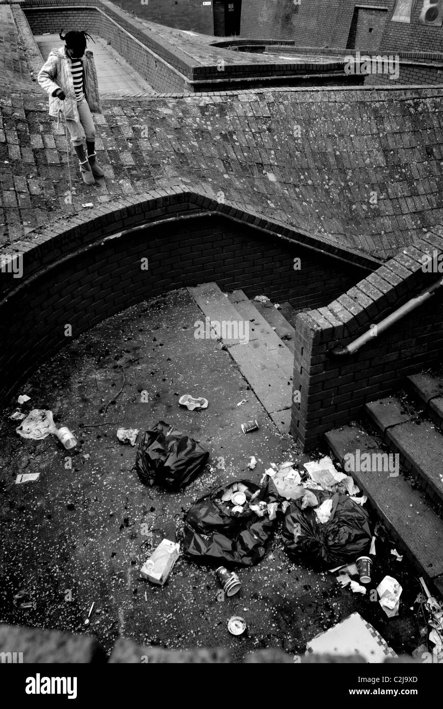 Sentiero pubblico con lettiera / rifiuti oggetto di dumping in ambiente urbano. (Fly ribaltamento) con la ragazza che guarda. Foto Stock