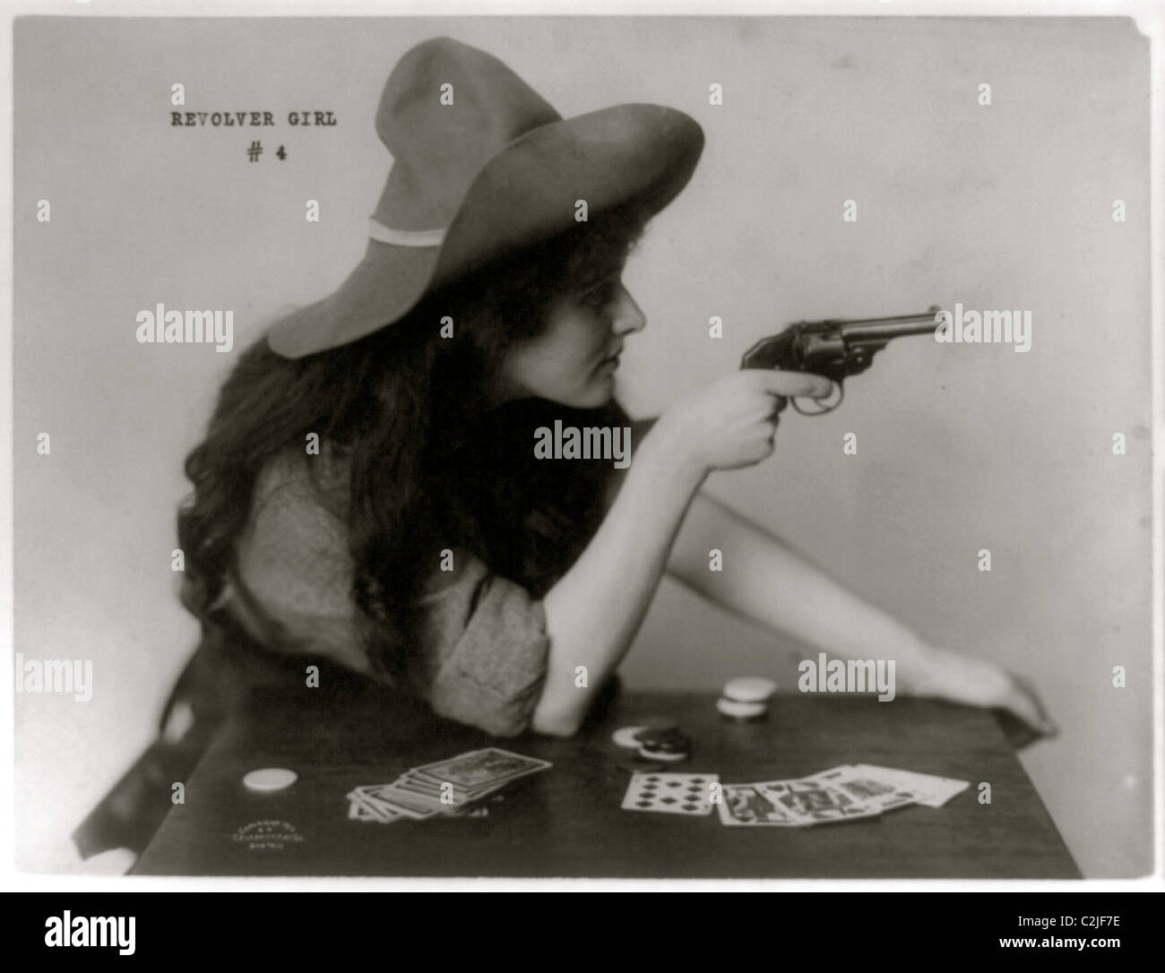 Giovani Cowgirl tenere pistola su una tavola di carte da gioco Foto Stock