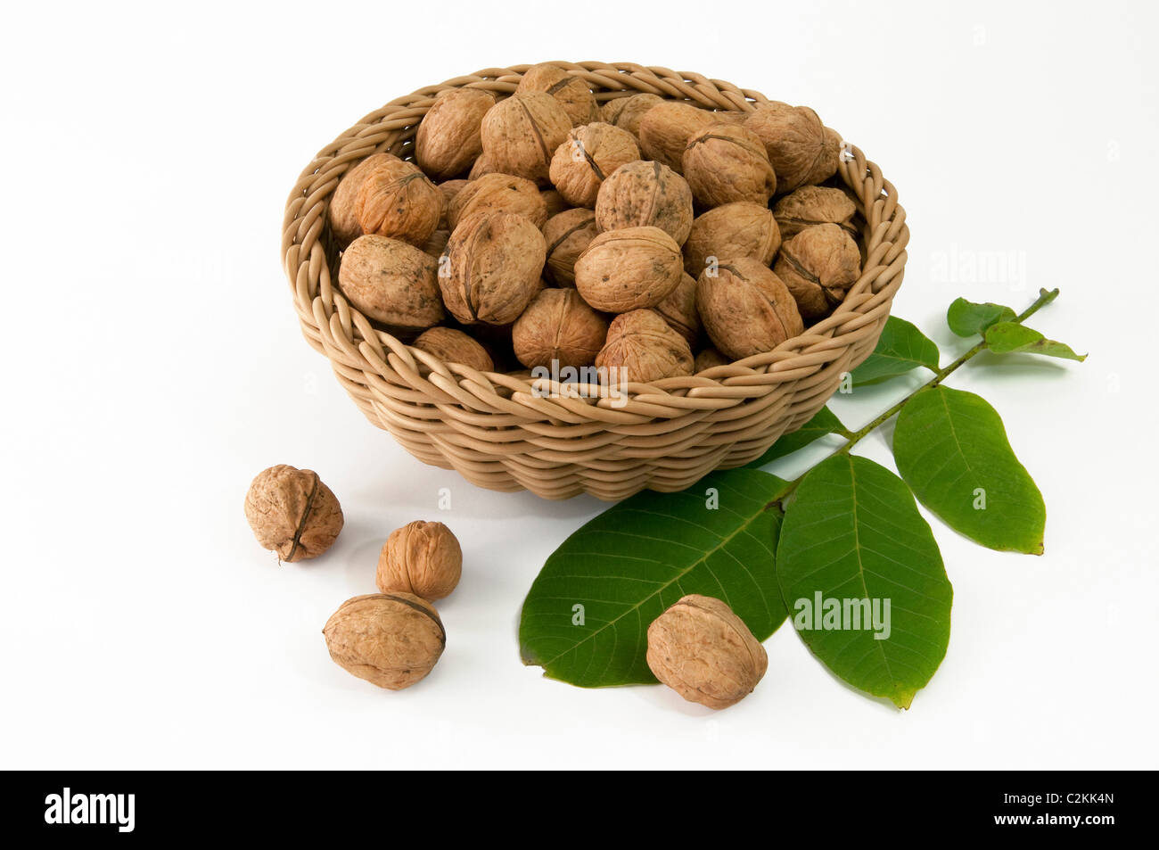 Noce Inglese, Persiano Noce (Juglans regia). Dadi in un cesto e foglia. Studio Immagine contro uno sfondo bianco. Foto Stock