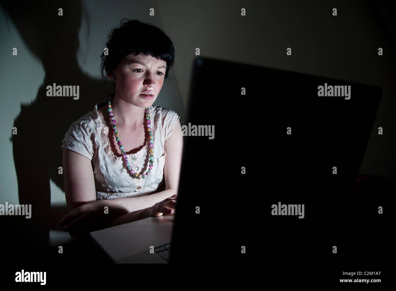 Una giovane donna UK università studenti che lavorano sul suo computer portatile nella sua camera da letto a casa Foto Stock