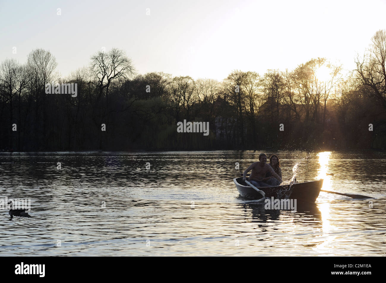 Matura in barca a remi sul lago al tramonto Foto Stock