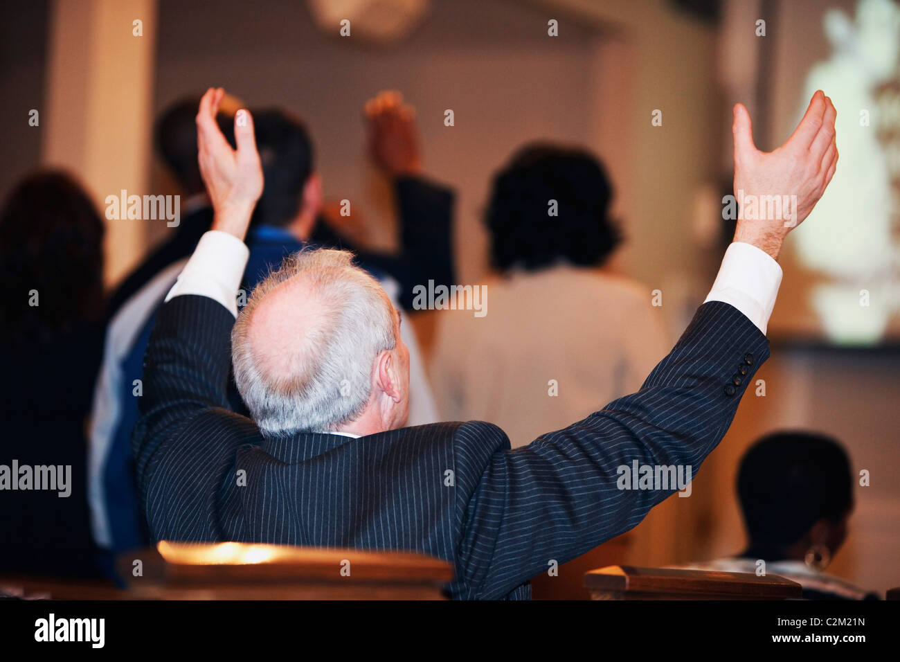 Un uomo seduto in chiesa con le mani alzate Foto Stock