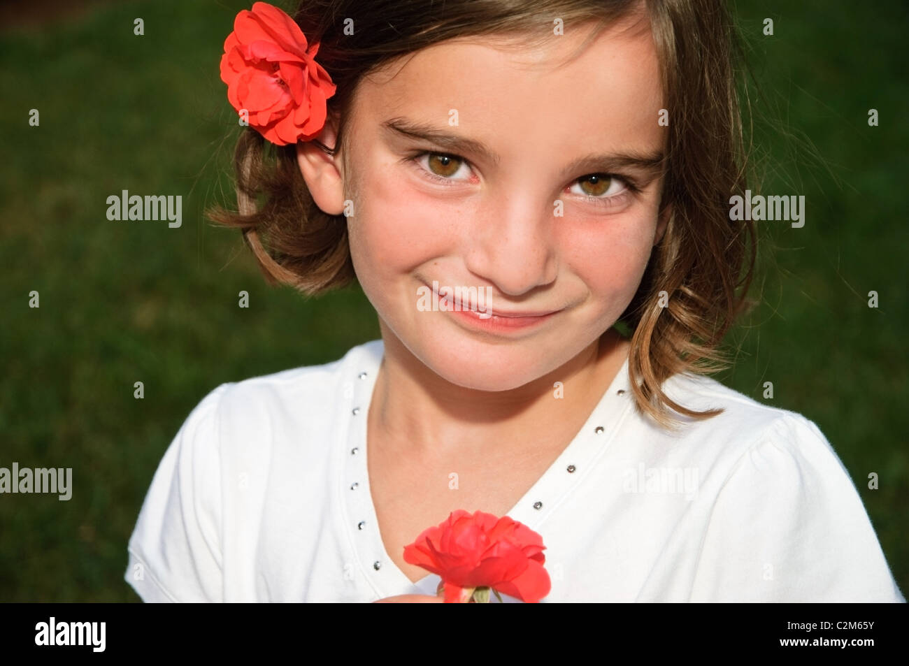Un simpatico giovane ragazza con una rosa e indossa uno tra i capelli. Foto Stock