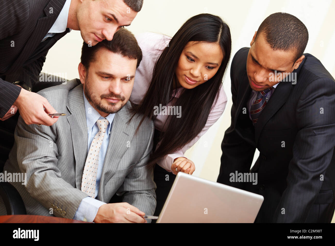 Imprenditore maturo mostra qualcosa su laptop al suo multi etnico team business Foto Stock
