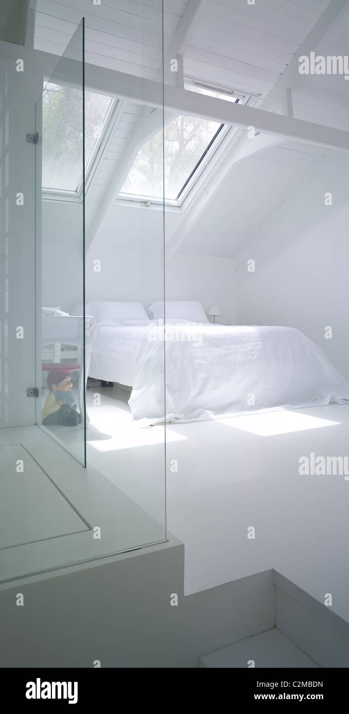 Moderna camera da letto bianca sotto la gronda e dietro le pareti di vetro Foto Stock