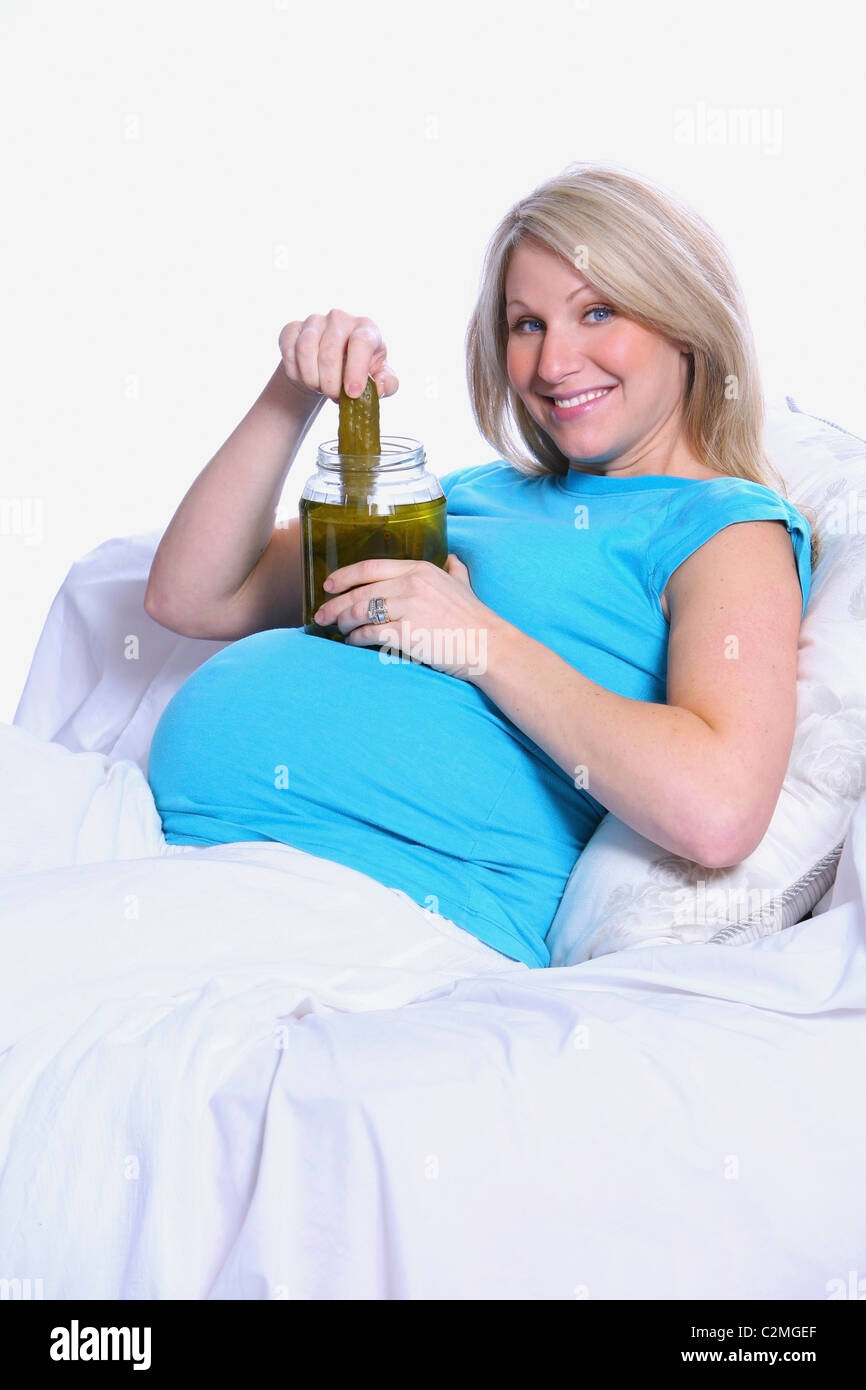 Donna incinta in letto con un barattolo di sottaceti Foto Stock
