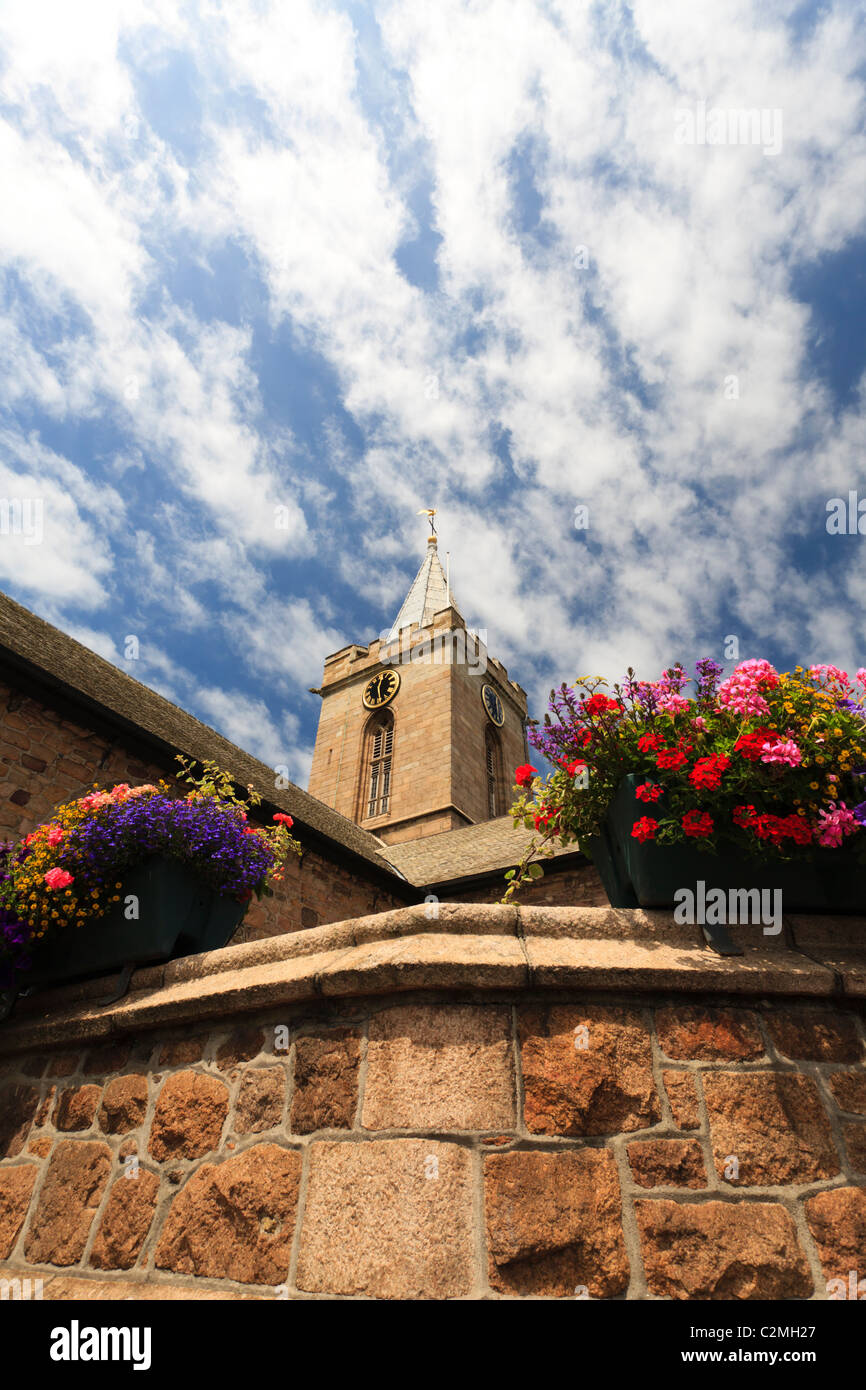 Torre di una chiesa con fiori in primo piano Foto Stock