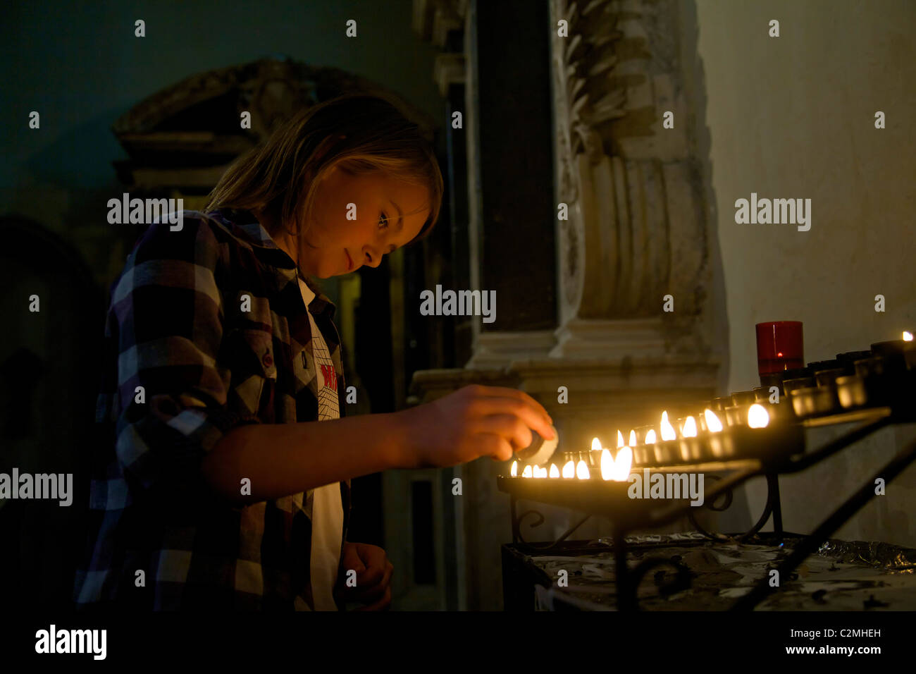 Ragazza giovane accensione di una candela votiva in Rochester Cathedral Foto Stock