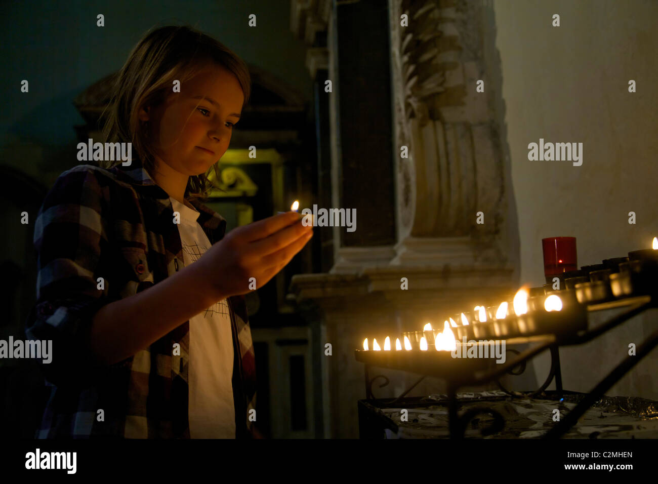 Ragazza giovane accensione di una candela votiva in Rochester Cathedral Foto Stock