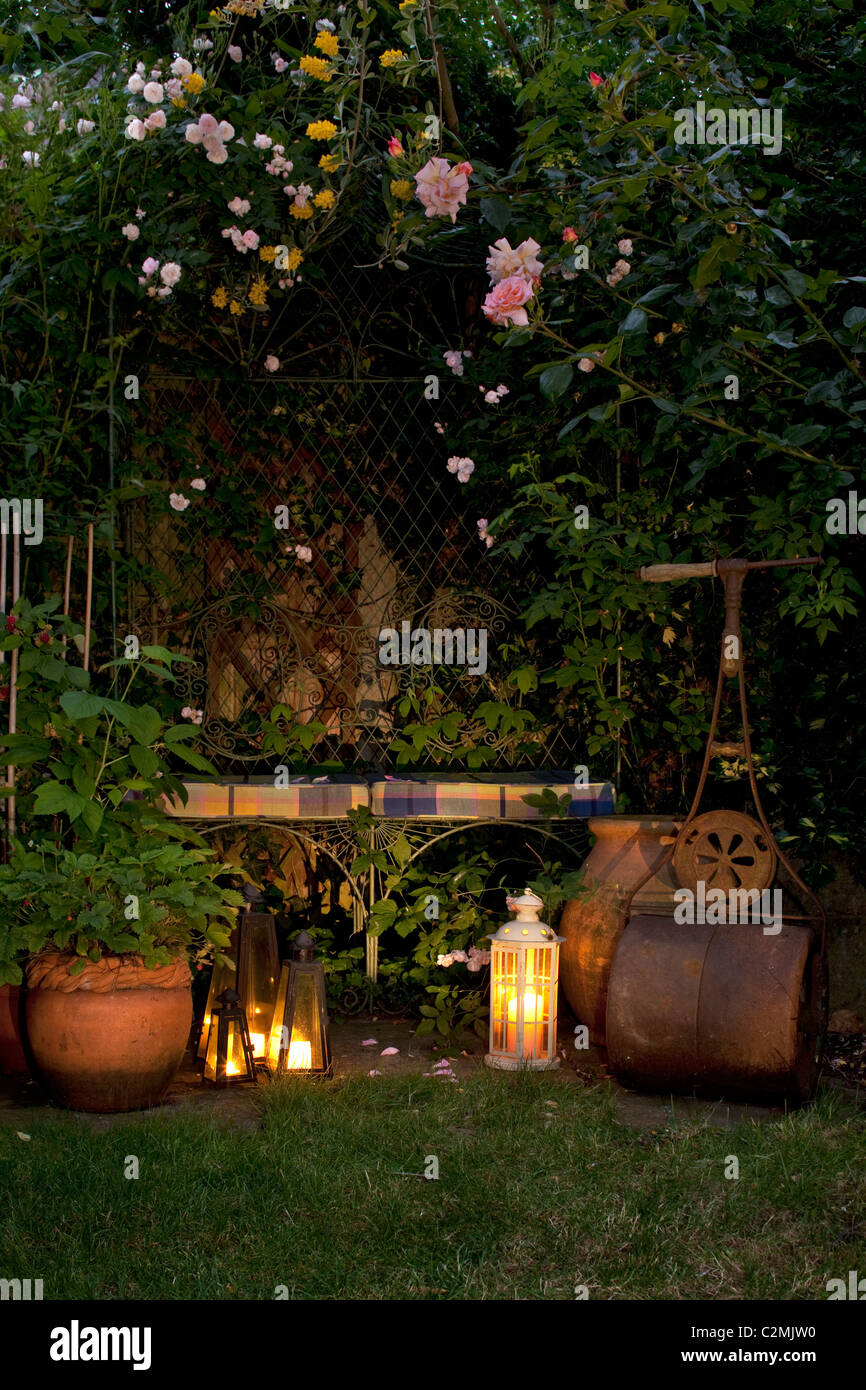 In estate il giardino suburbano al tramonto con il climbing rose rosa,  antico giardino rullo e lanterne accese Foto stock - Alamy