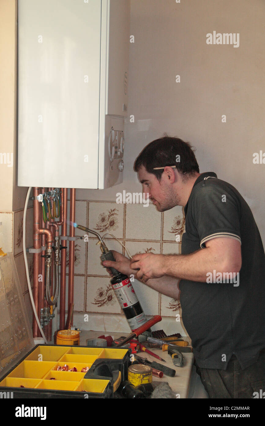 Un ingegnere di riscaldamento la saldatura di un tubo durante l'installazione di una nuova marca di valorosi caldaia a condensazione in un Regno Unito proprietà residenziale. Foto Stock