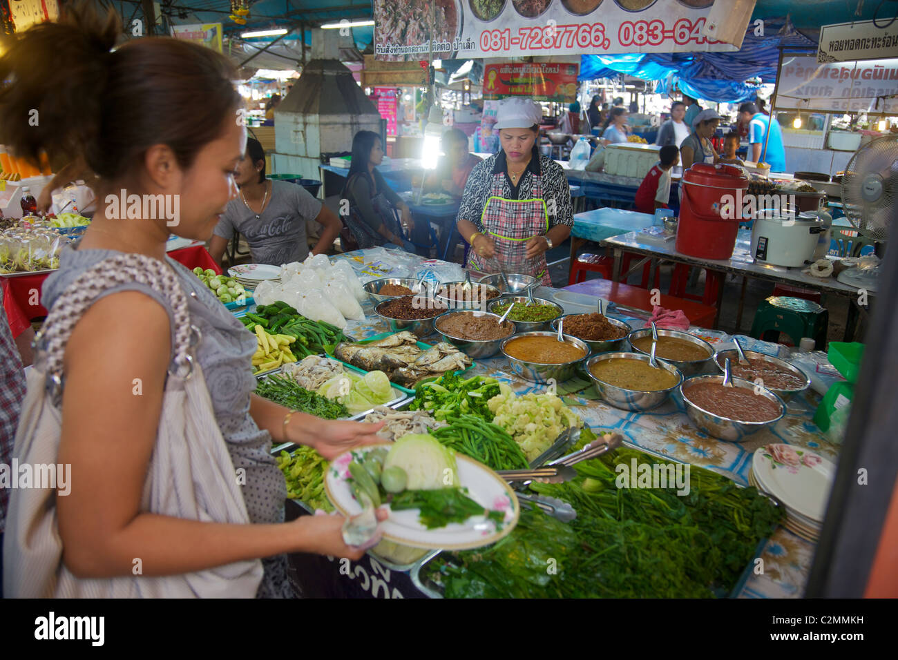 Una donna tailandese acquistare verdure per pranzo da un mercato in stallo, Phuket, Tailandia Foto Stock