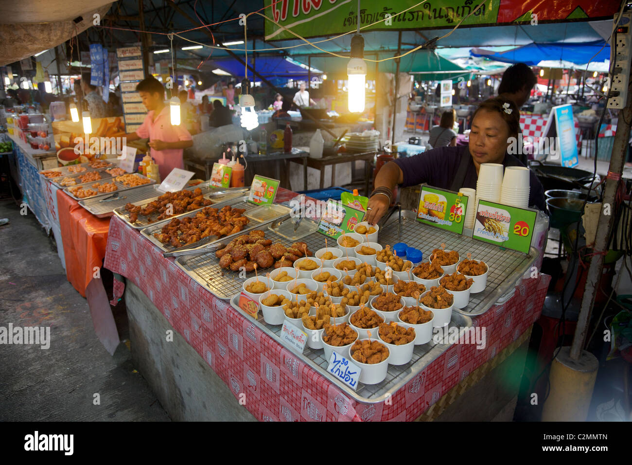 Un tailandese donna posa pepite di pollo e patatine fritte, su un mercato in stallo, Phuket, Tailandia Foto Stock