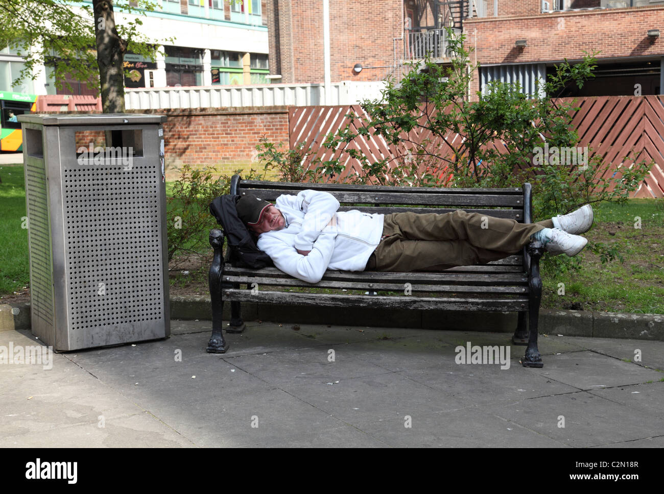 Un uomo addormentato su un banco di lavoro in una città del Regno Unito. Foto Stock