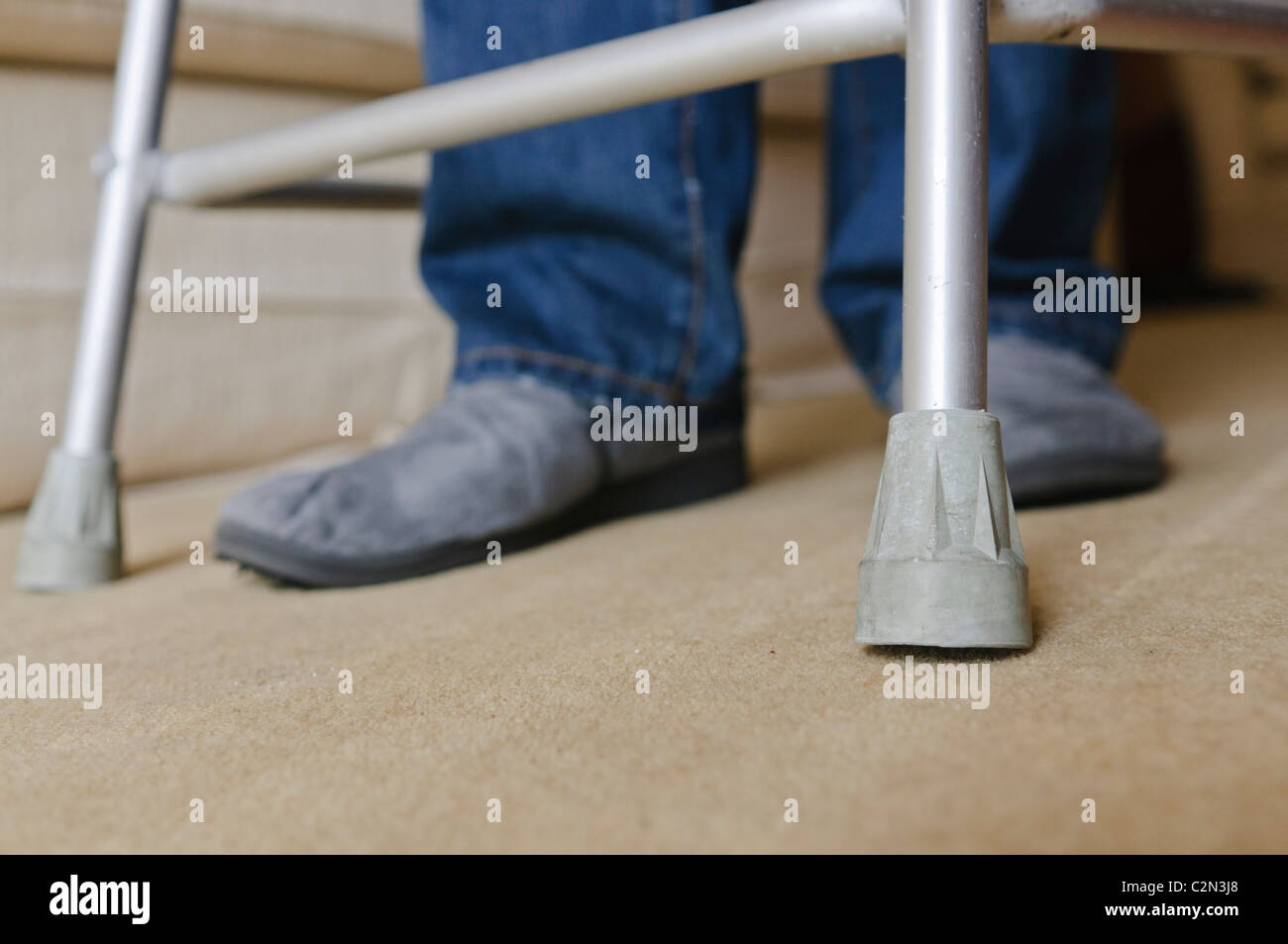 L uomo nella sua 40's utilizzando una assistenza a piedi telaio a causa di incapacità a camminare a causa di artrite reumatoide e dolorosa delle articolazioni. Foto Stock