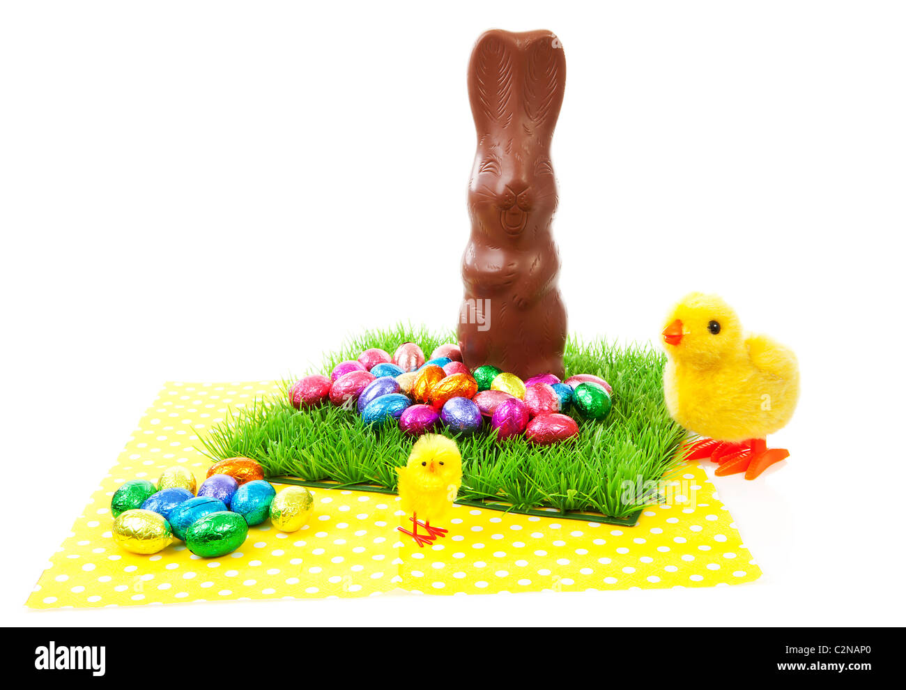 Scenario di Pasqua: coniglio di cioccolato e uova colorate sul tovagliolo su sfondo bianco Foto Stock