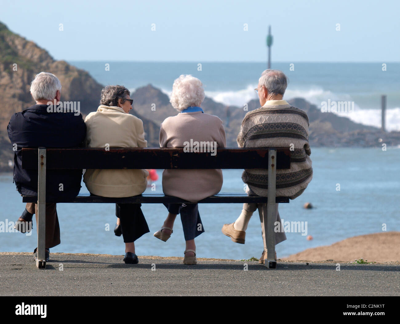 Quattro persone vecchio seduto su una panchina che guarda al mare, Bude, Cornwall, Regno Unito Foto Stock