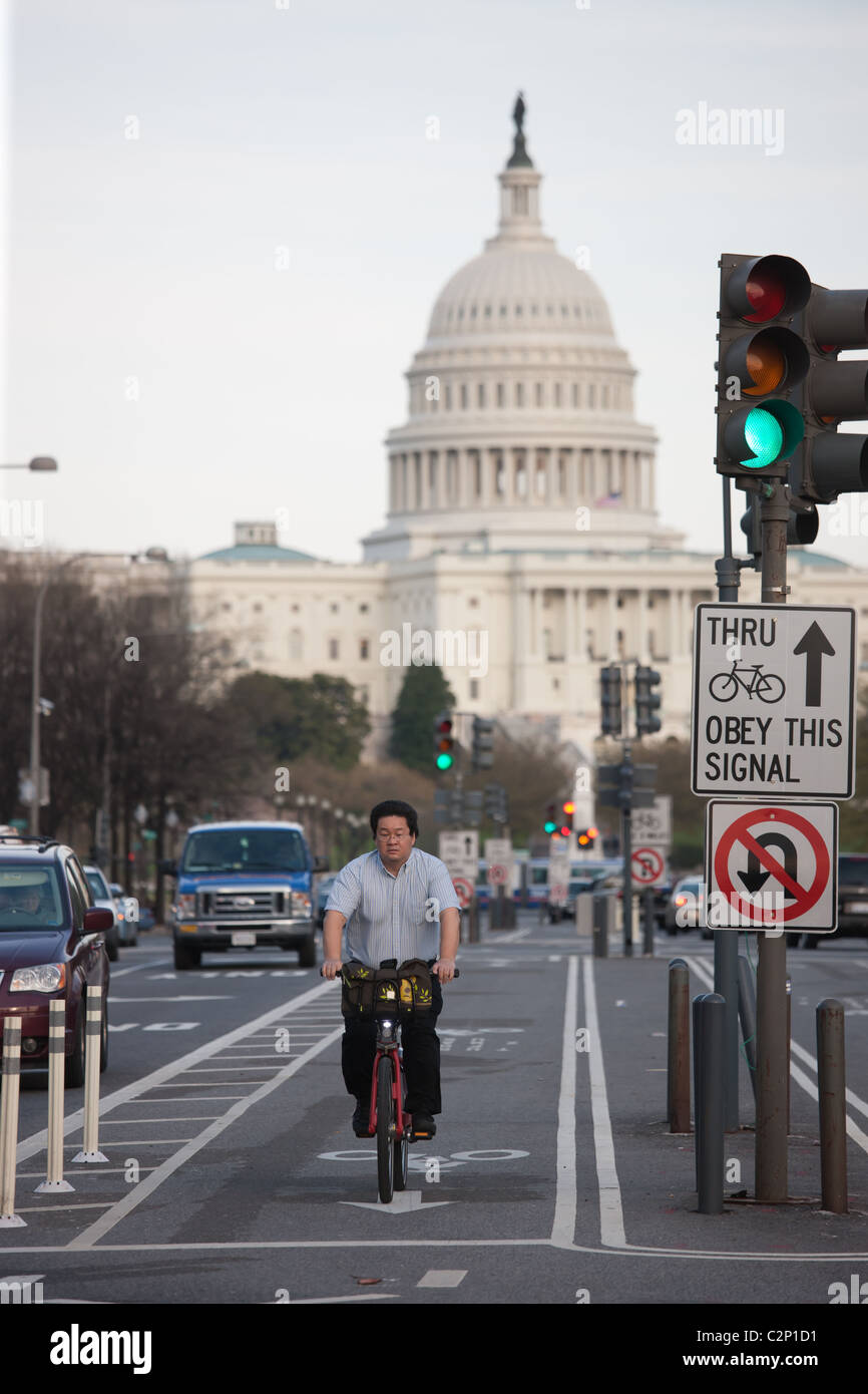 Una bicicletta commuter cavalca un Capital Bikeshare bike nei due-modo protetto pista ciclabile su Pennsylvania Avenue a Washington, DC. Foto Stock