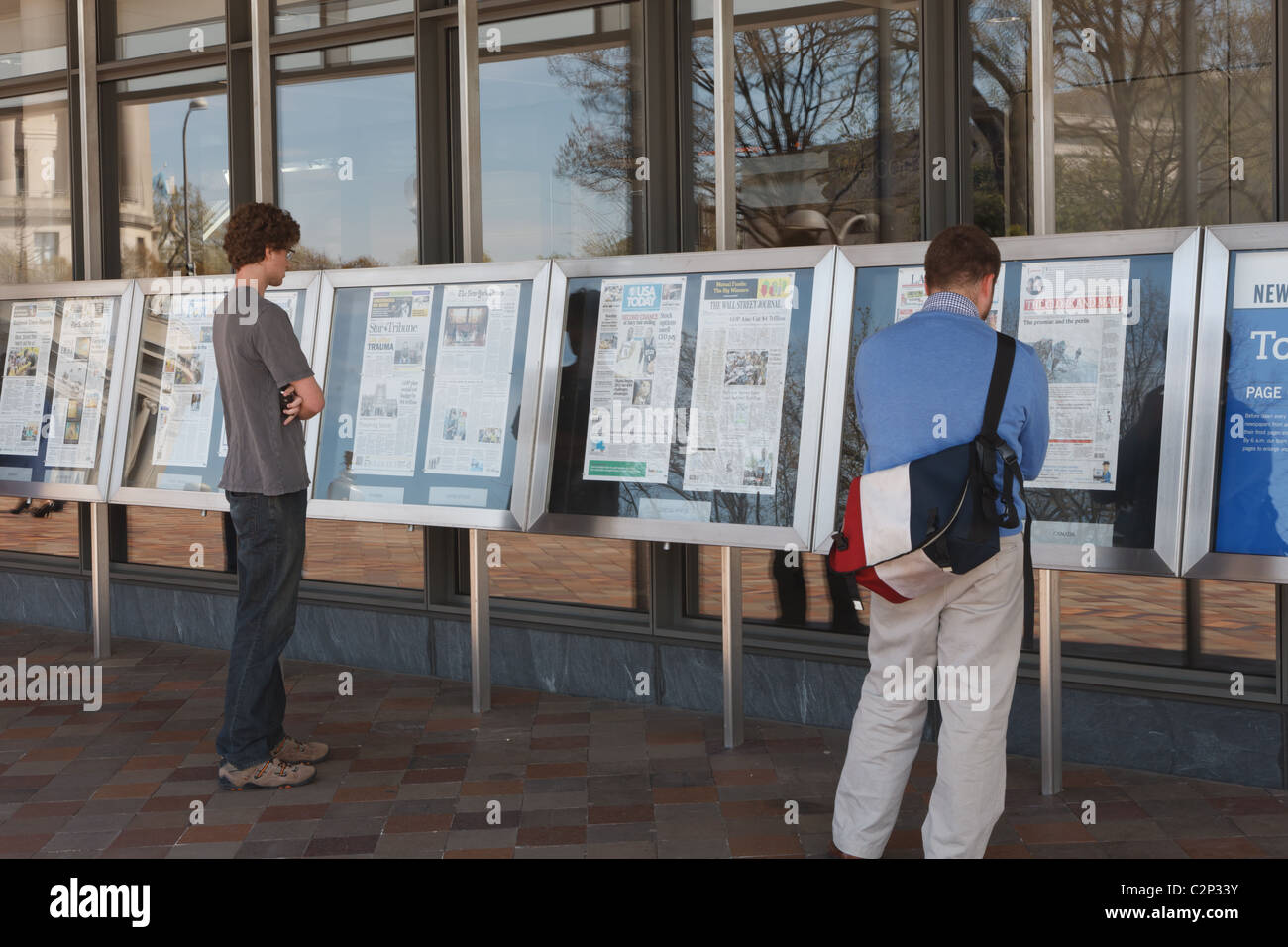 La gente di leggere le pagine anteriori della giornata di quotidiani di fronte al museo Newseum di notizie di Washington DC. Foto Stock